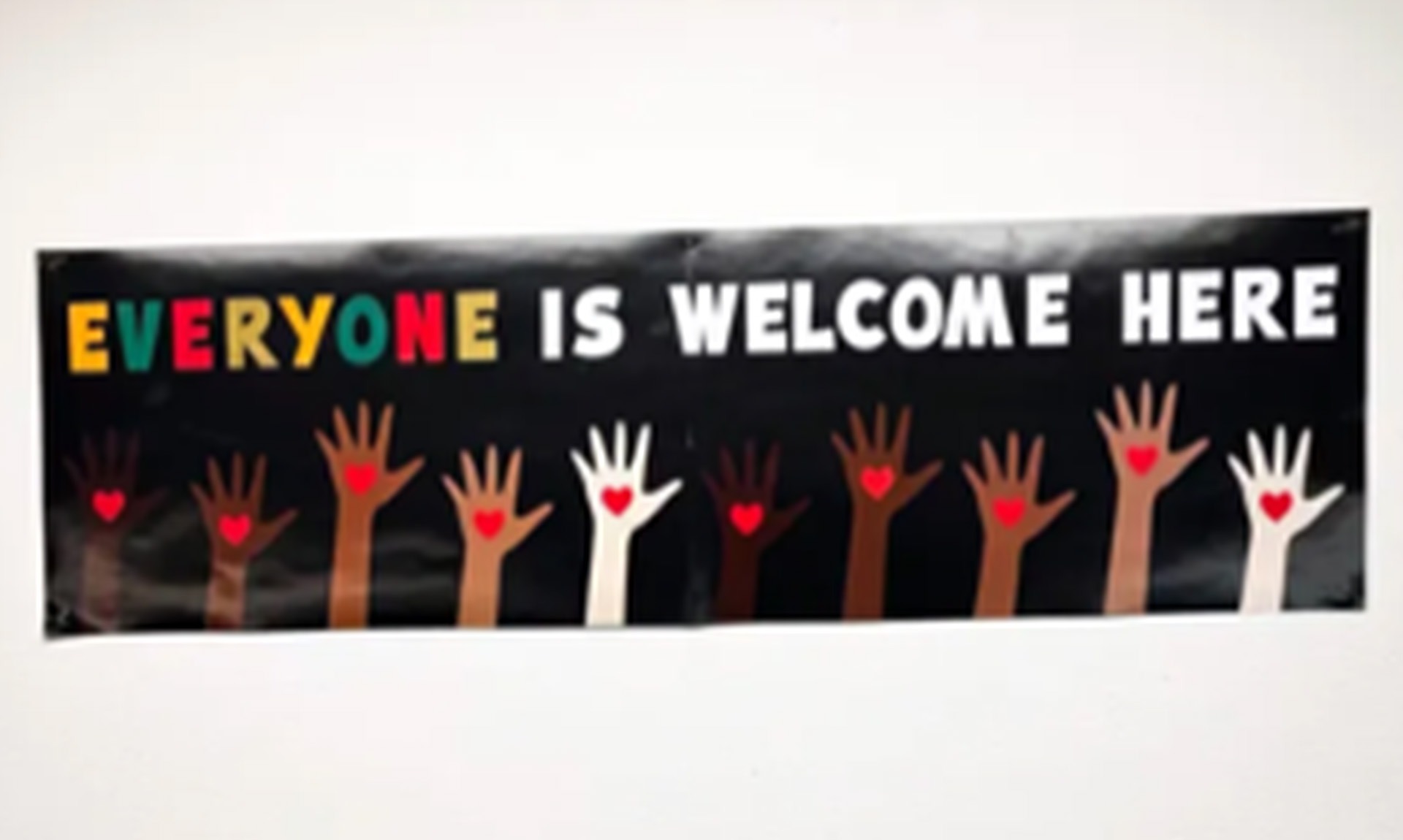 Poster in classroom that reads 'Everyone is Welcome Here' with diverse raised hands