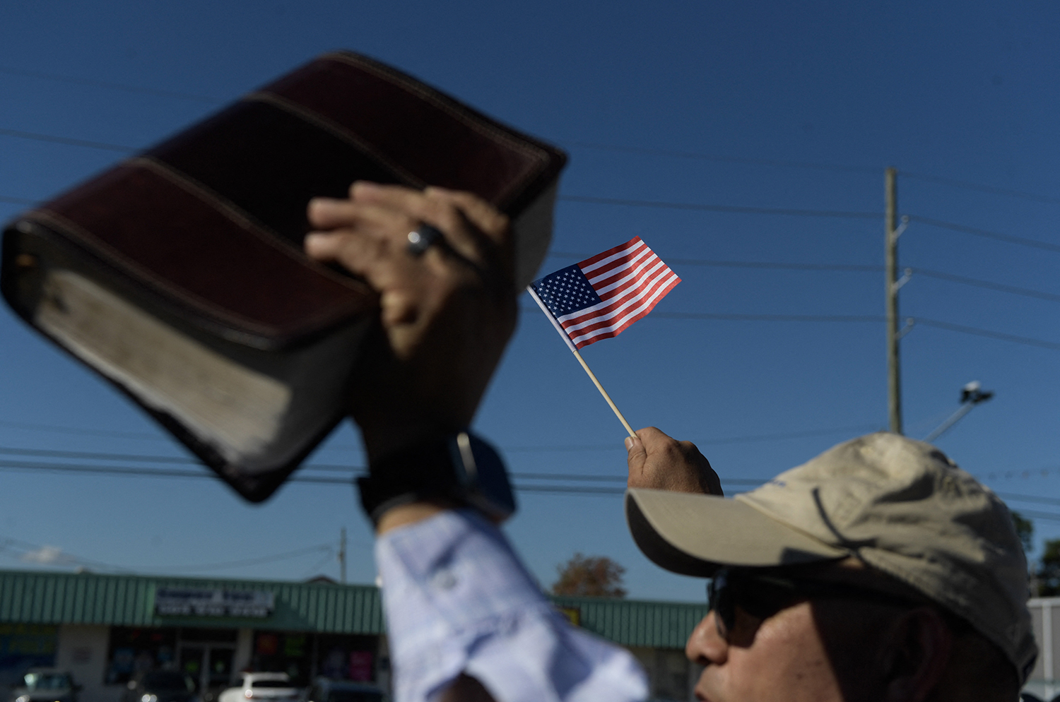 A protester holds a Bible and an American flag during a demonstration against ICE and Border Patrol activity in Kenner, Louisiana.