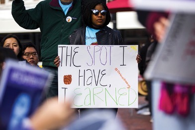 Student holding a protest sign reading “The spot I have earned” during a demonstration about affirmative action and educational access.