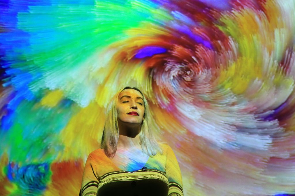 Woman reflecting against a colorful abstract background, illustrating spirituality and reflection in the age of AI